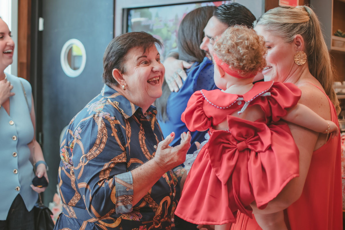 Uma mulher de idade sorrindo para uma bebê durante a festa de aniversário de um ano dela.