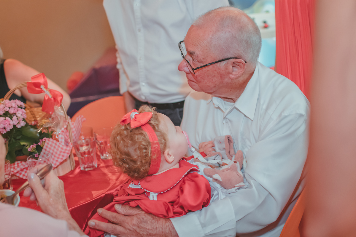 uma bebê, olhando para seu avó, durante sua festa de aniversário de 1 ano.
