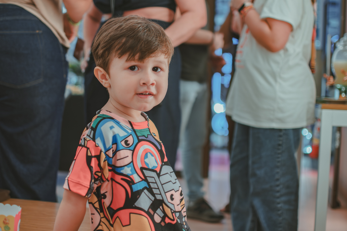 Um menino olhando para a camera com um leve sorriso em sua festa de aniversário.