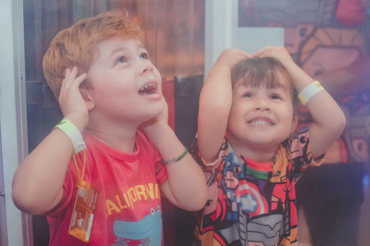 Dois meninos brincando em uma cabine que cai bolinhas de plastico, durante um aniversário no playcenter family.