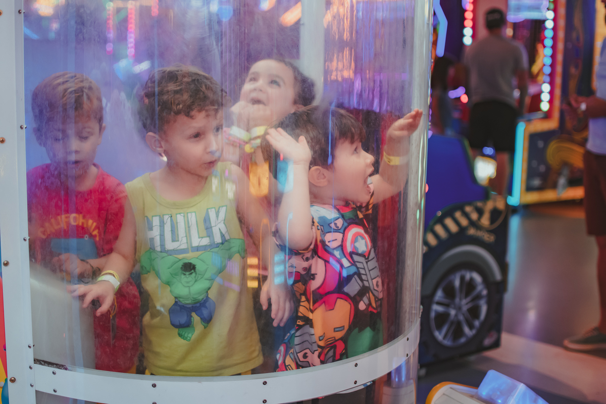 Quatro crianças brincando em uma cabine que cai bolinhas de plastico, durante um aniversário no playcenter family.