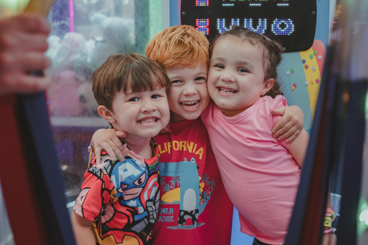 3 crianças abraças e sorrindo dentro de um brinquedo do playcenter family durante uma festa de aniversário.