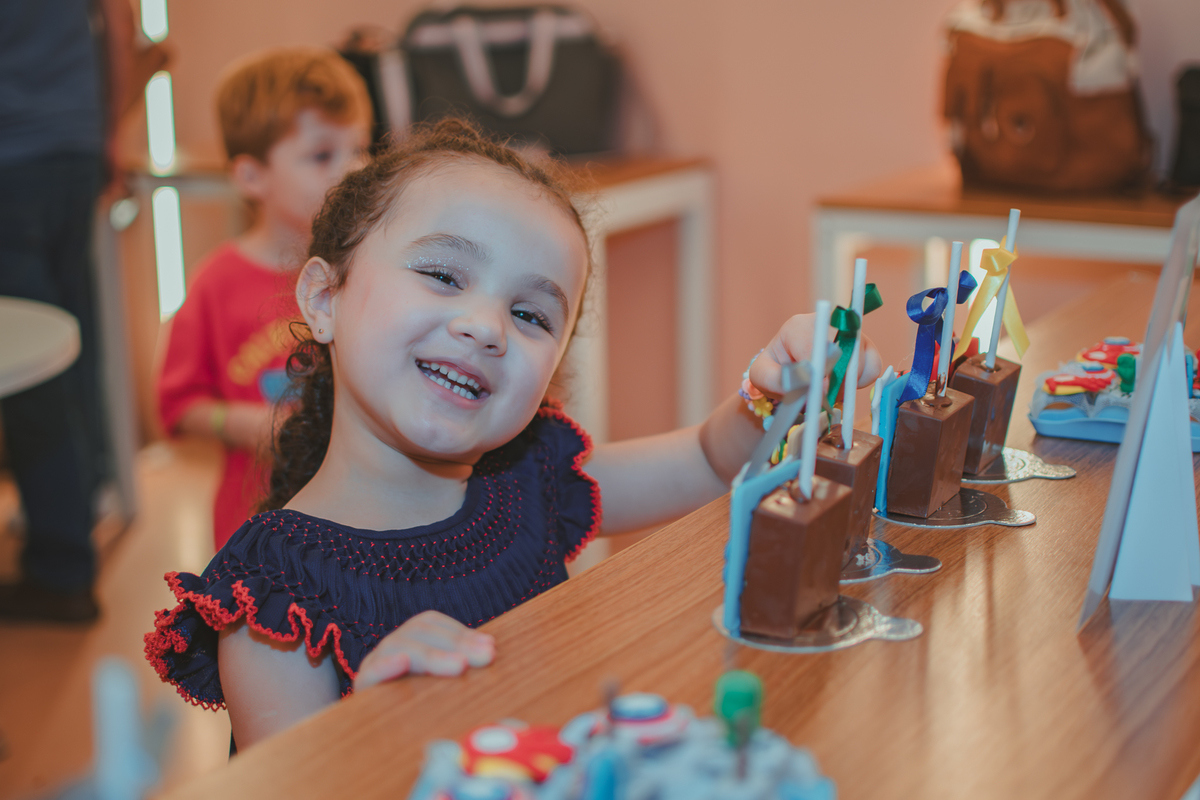 Uma menina sorrindo e apontando um doce personalizado de uma festa de aniversário.