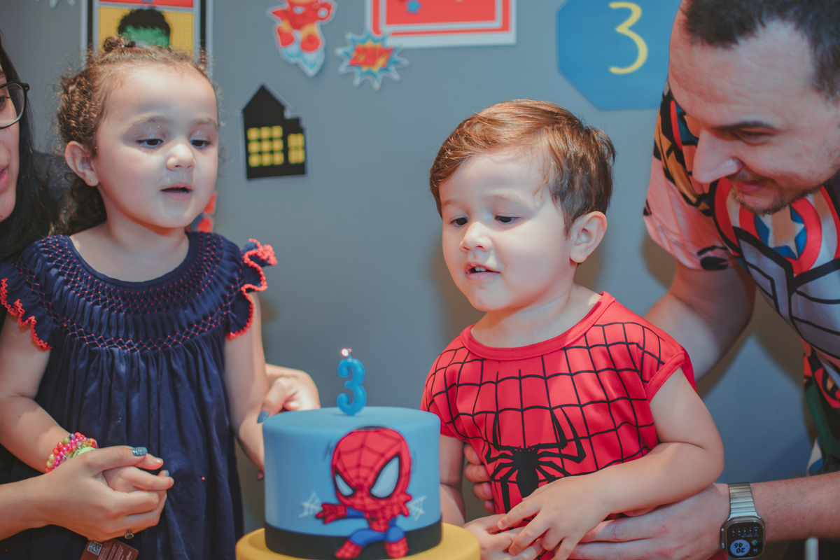 Duas crianças assoprando uma vela de aniversário.