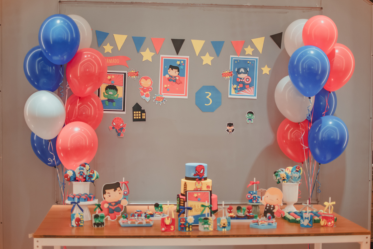mesa de bolo decorada com balões vermelhos azul e branco com tema de super heróis.
