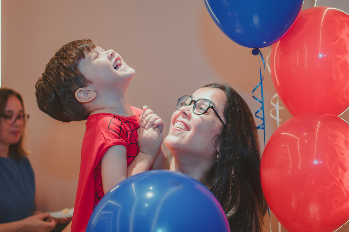 Um menino e  sua mãe estourando um balão de festa.
