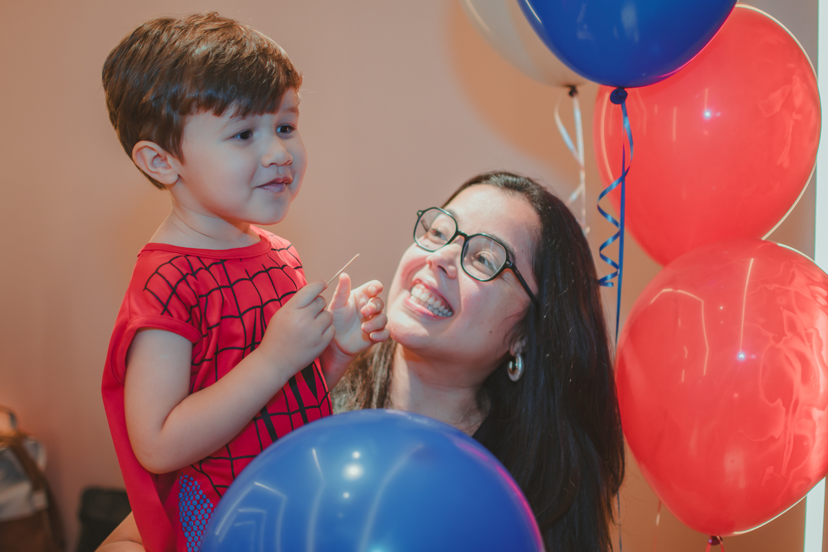 Um menino e  sua mãe estourando um balão de festa.