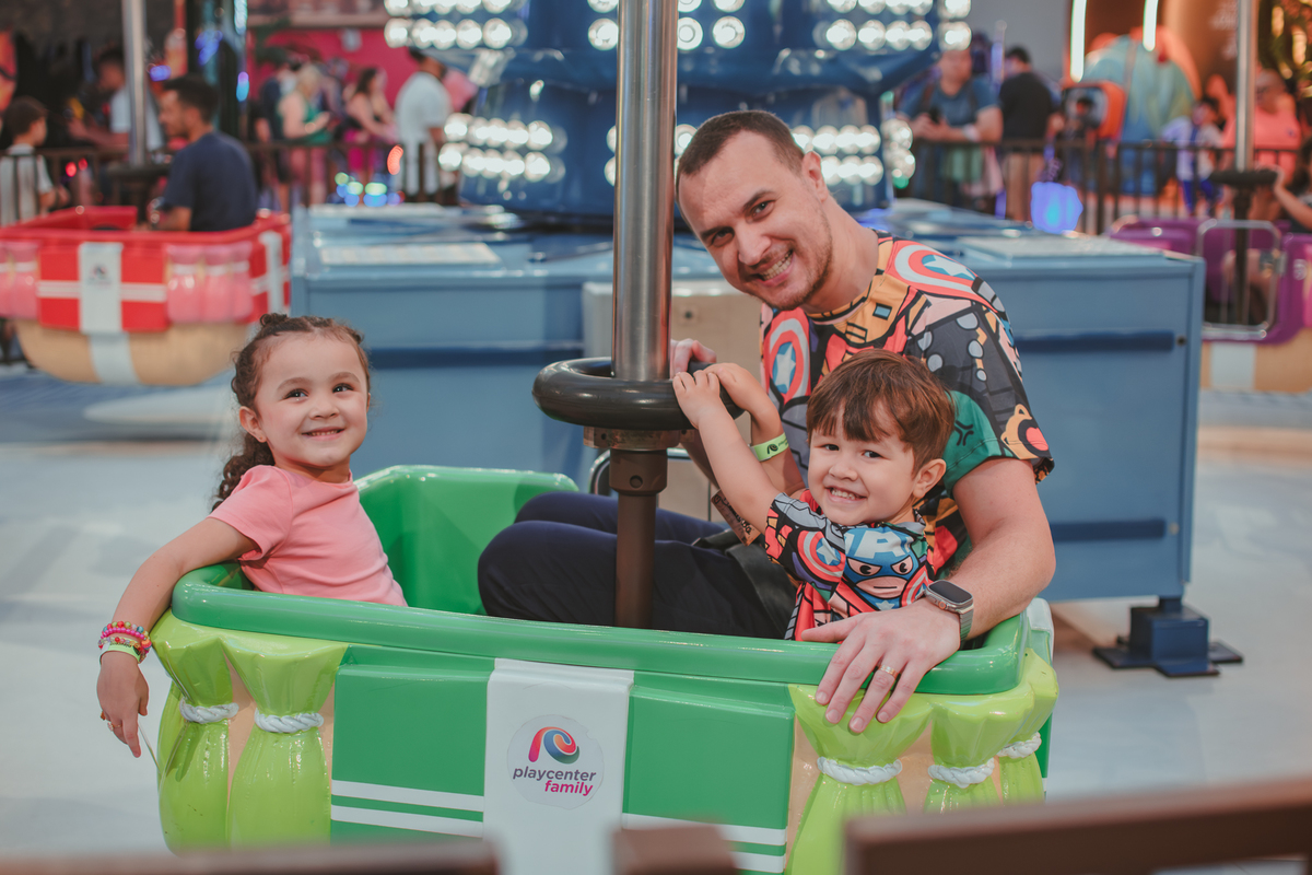 Uma homem e duas crianças em um brinquedo que gira no playcenter family em Santo Andre, durante uma festa de aniversário infantil.