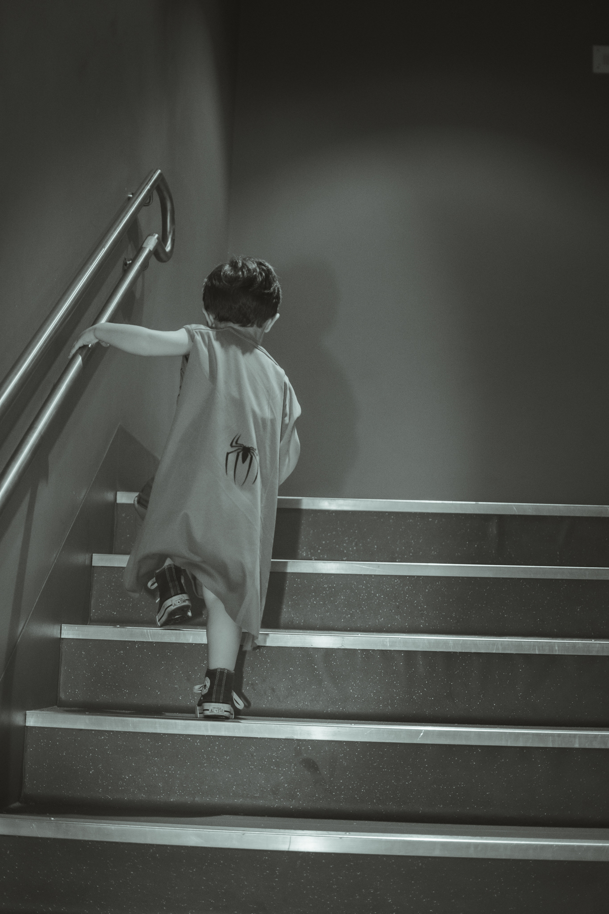 Um menino vestido de homem aranha, subindo escadas, durante sua festa de aniversário.