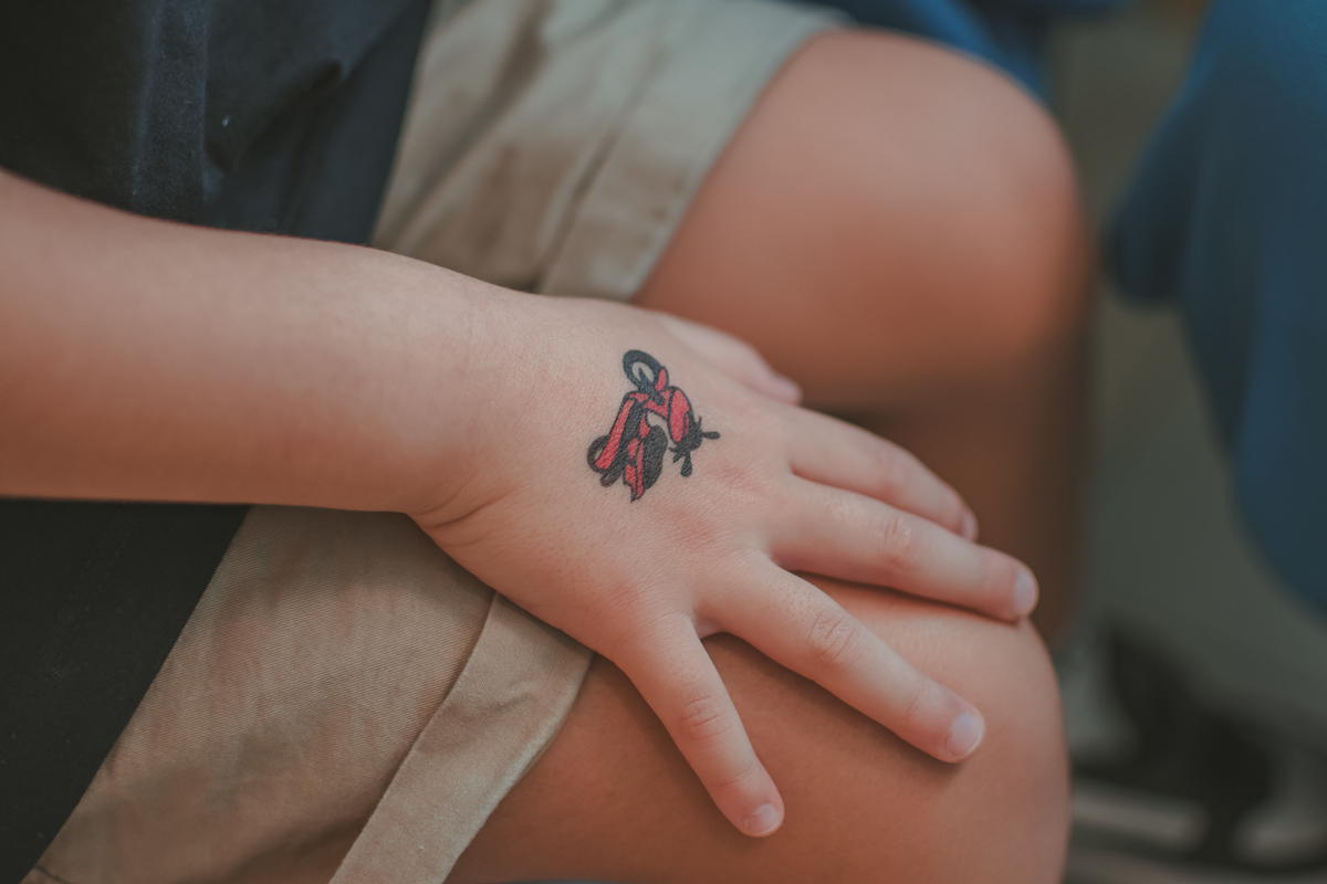 mãos pequenas de uma menino de 4 anos com a tatuagem falsa de uma moto, durante uma festa de aniversário infantil.