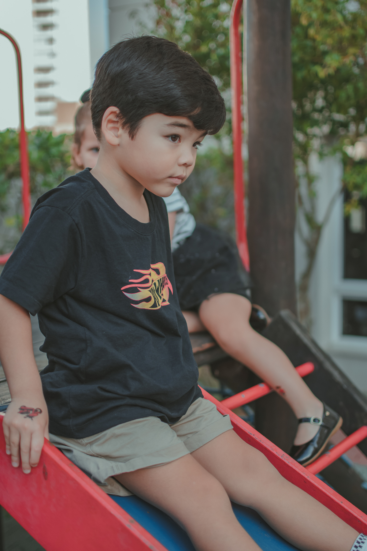 Um menino de camiseta preta brincando de descer no escorregador, durante sua festa de aniversário.