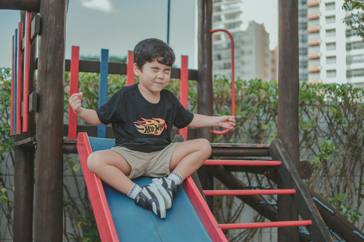 m menino de camiseta preta brincando de descer no escorregador, durante sua festa de aniversário.