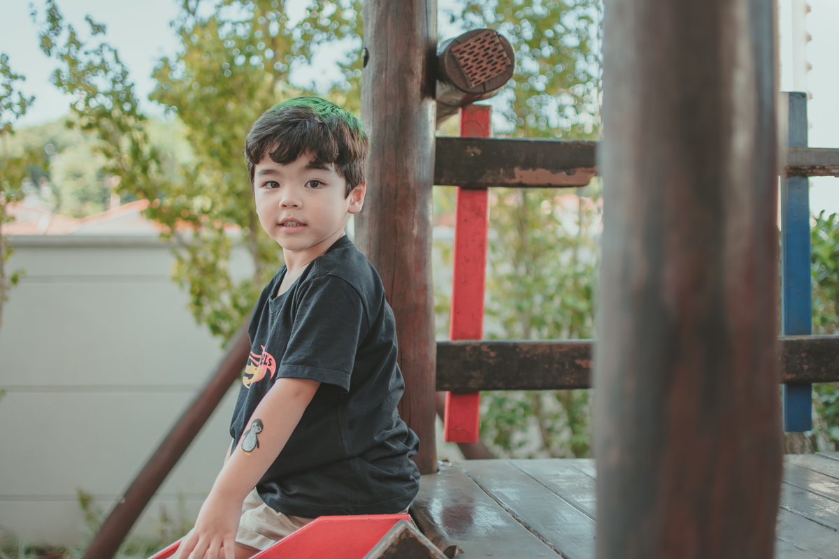 m menino de camiseta preta brincando de descer no escorregador, durante sua festa de aniversário.