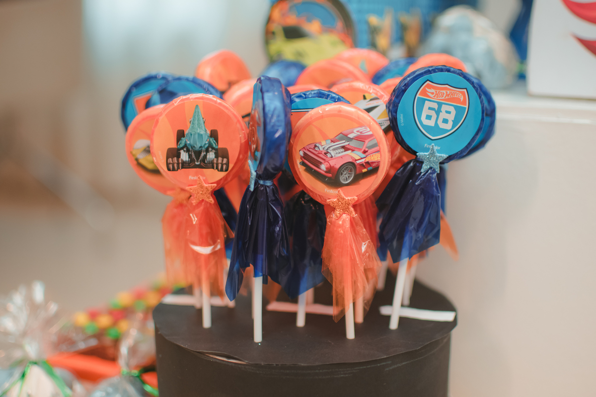 Pirulitos embalados com saquinhos azul e laranja, combinando com o tema de aniversário Hot Wheels.