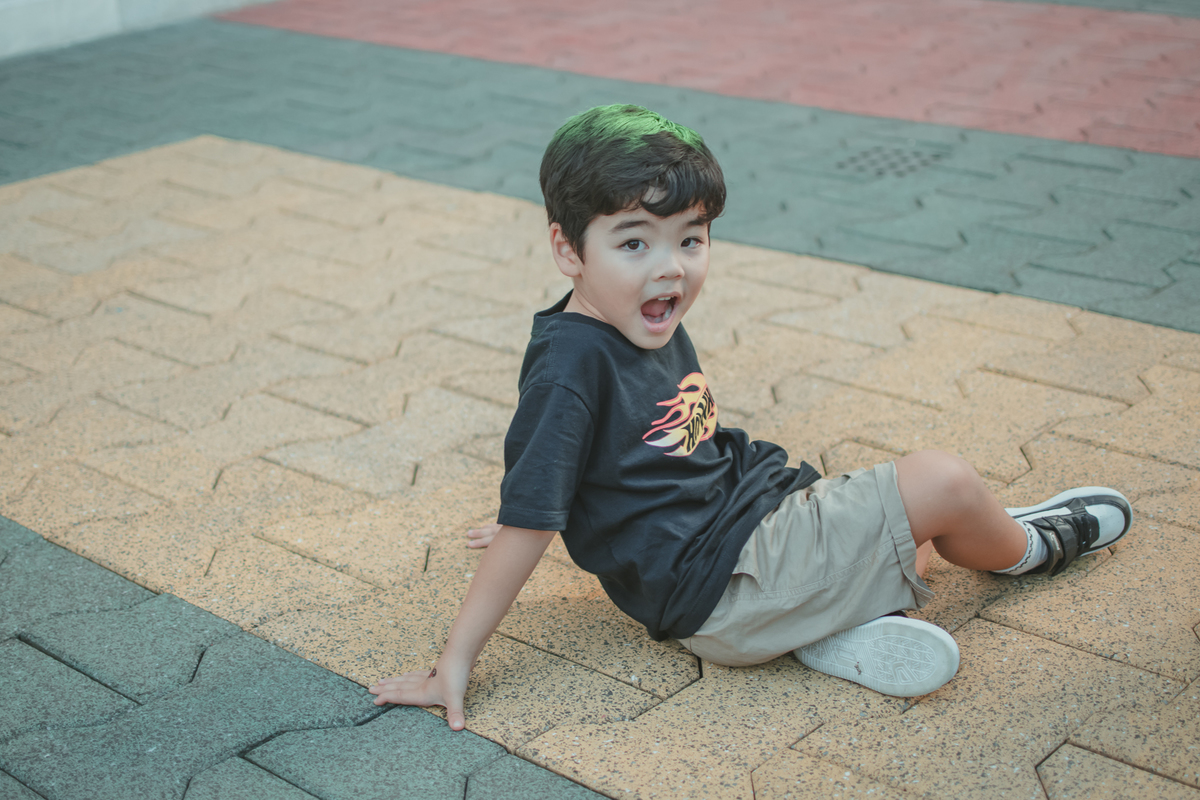 Um menino sentado ao chão e sorrindo, durante seu aniversário de 4 anos.