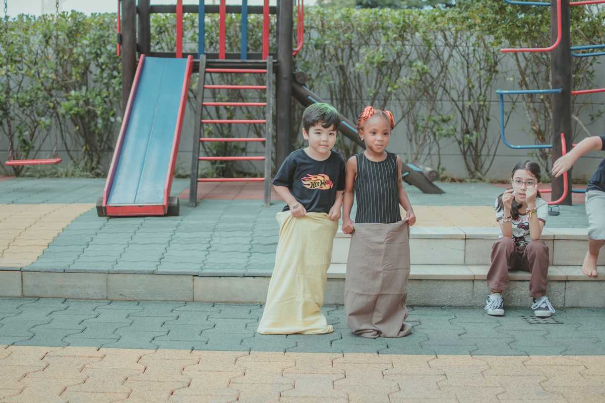 Um menino e uma menina vestidos de preto,  brincando de pular com  o saco, durante seu aniversário de 4 anos.