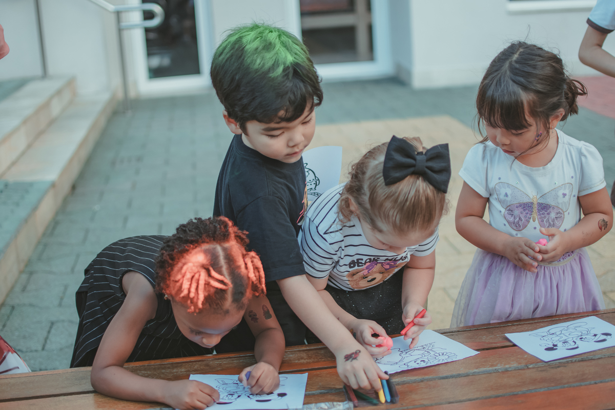 Varias crianças brincando de pintar durante uma festa de aniversário infantil.