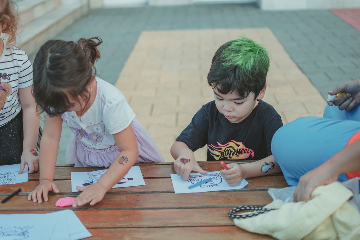 Varias crianças brincando de pintar durante uma festa de aniversário infantil.