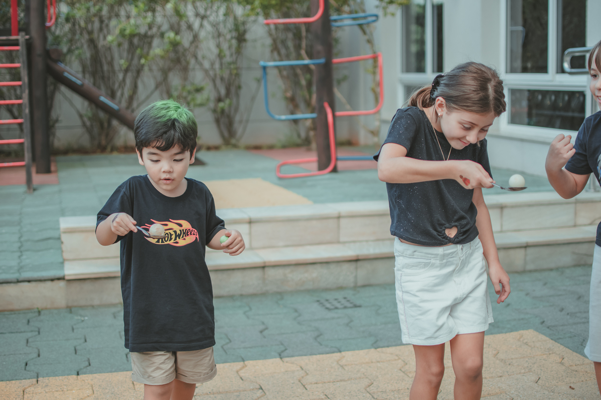 duas crianças brincando da brincadeira do ovo na colher, durante uma festa de aniversário infantil.
