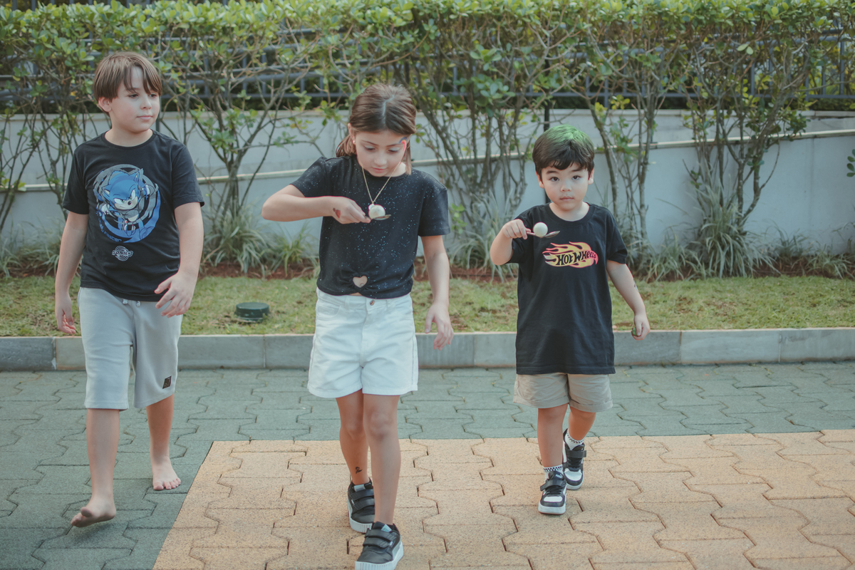duas crianças brincando da brincadeira do ovo na colher, durante uma festa de aniversário infantil.