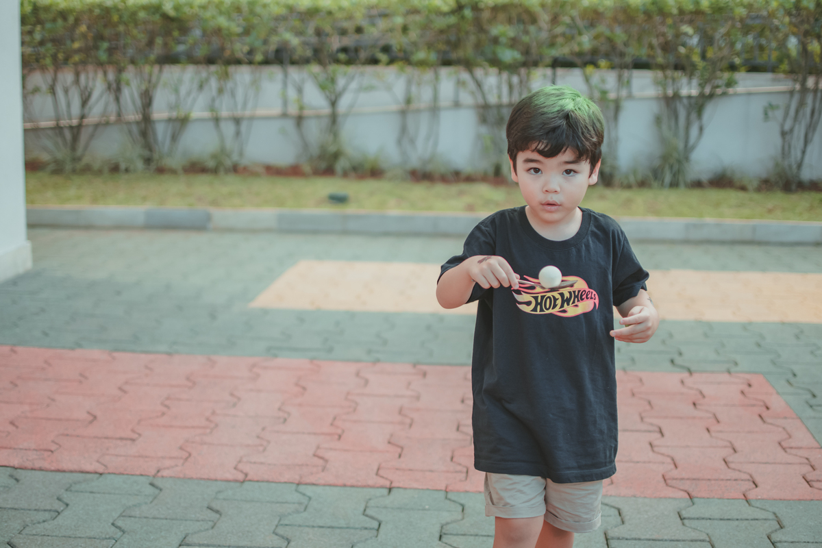 Uma crianças brincando da brincadeira do ovo na colher, durante uma festa de aniversário infantil.