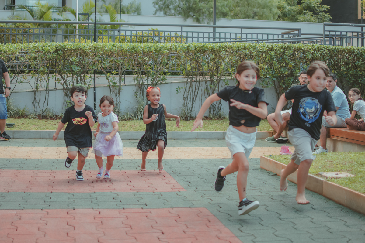 Varias crianças brincando de correr durante um aniversário infantil.