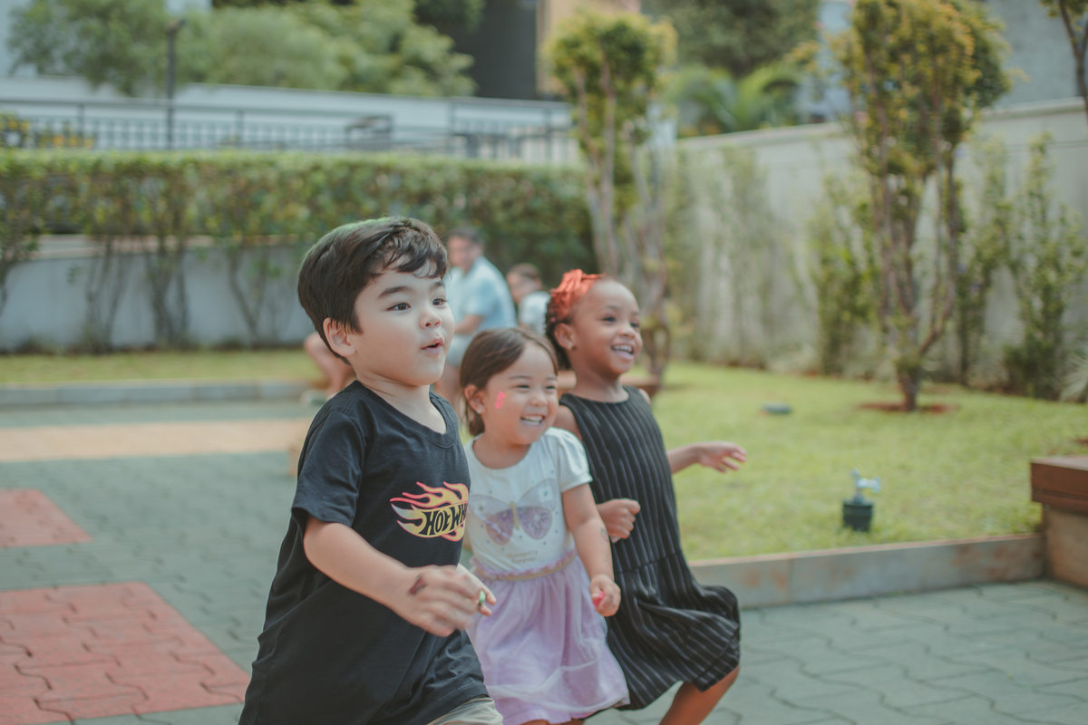 Varias crianças brincando de correr durante um aniversário infantil.