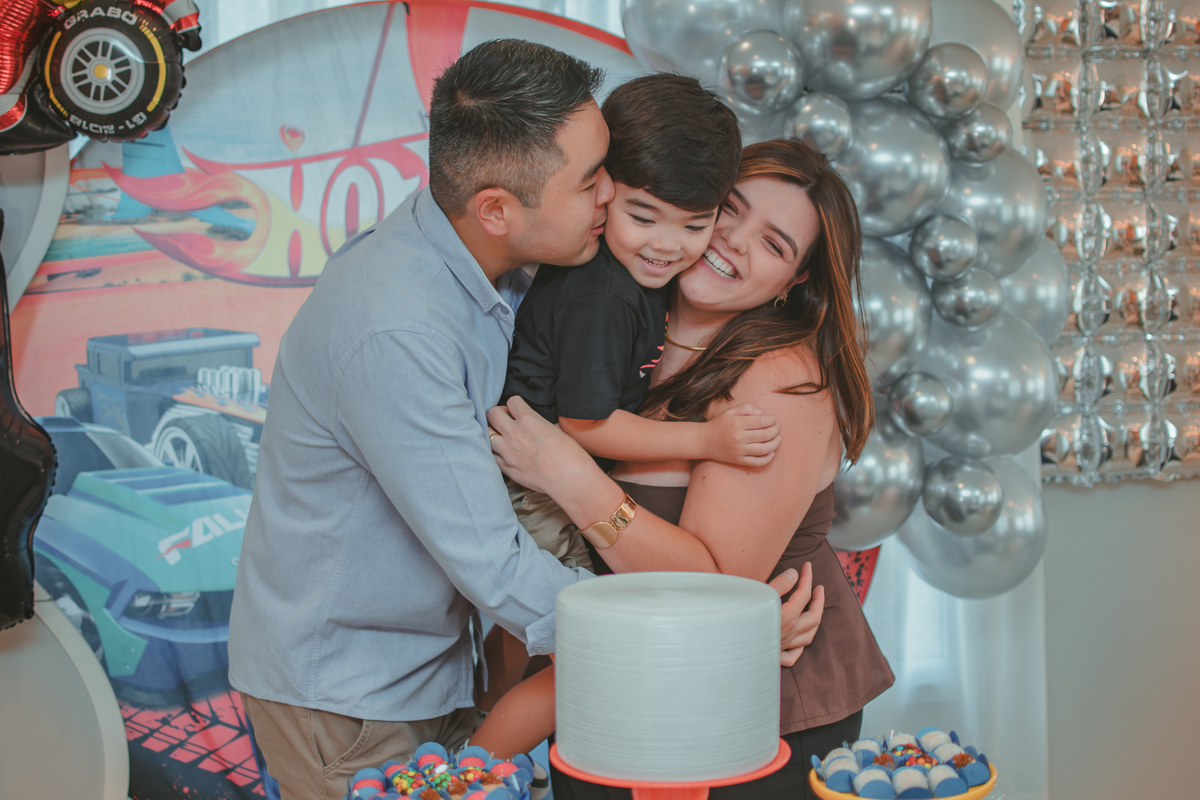Uma familia com um menino de 4 anos em seu aniversário em casa, com tema Hot Wheels.