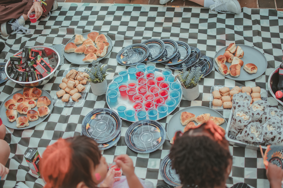 toalha de piquinique xadreza, com comidas varias para crianças durante uma festa de aniversário infantil.