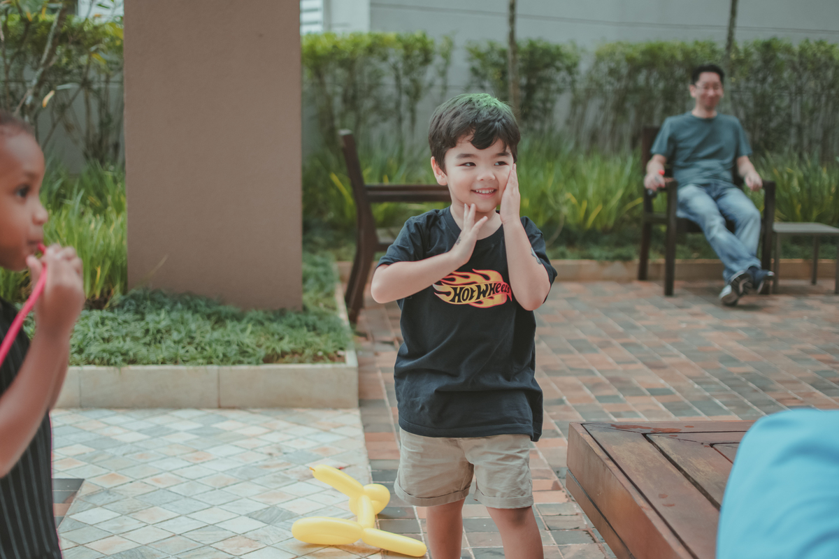 Um menino observando bexigas estourar, durante brincadeira em sua festa de aniversário.