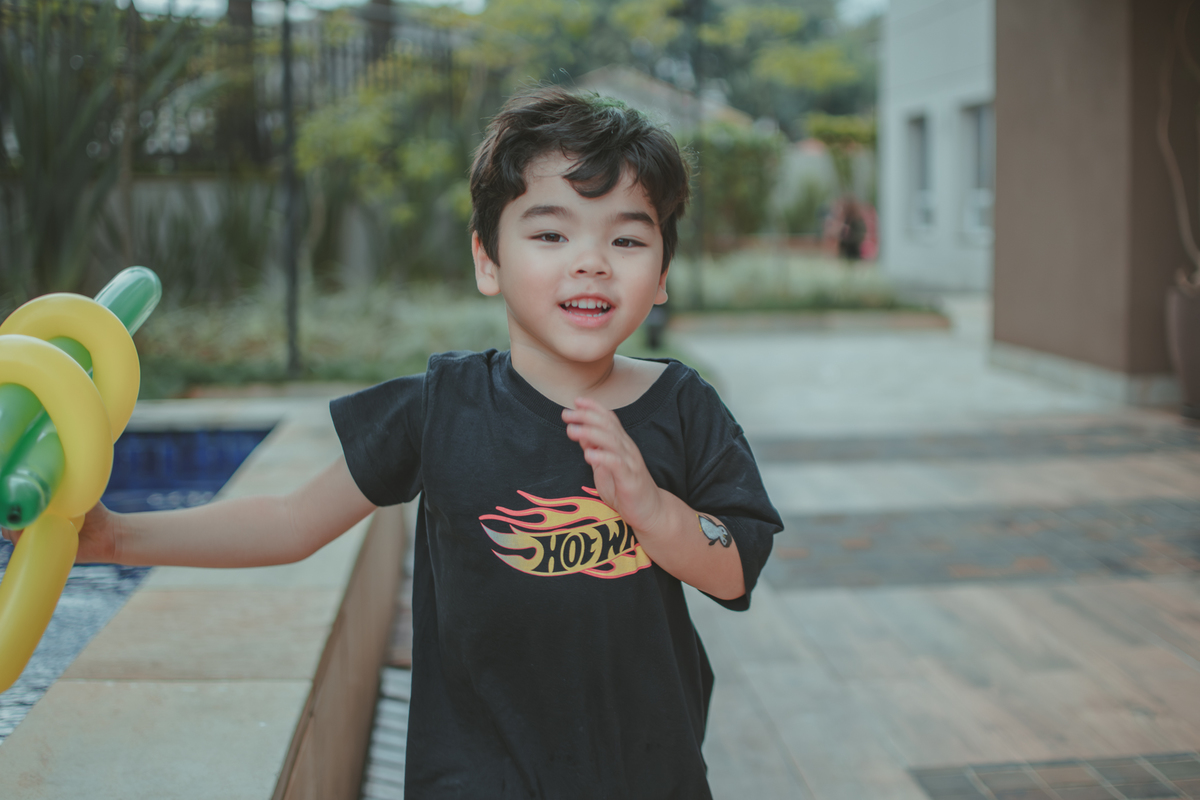 Um menino brincando com escultura de bexiga, durante sua festa de aniversário.