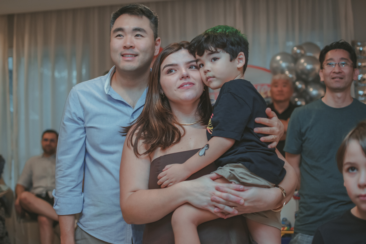Uma familia abraçada, durante retrospectiva em festa de aniversário infantil.