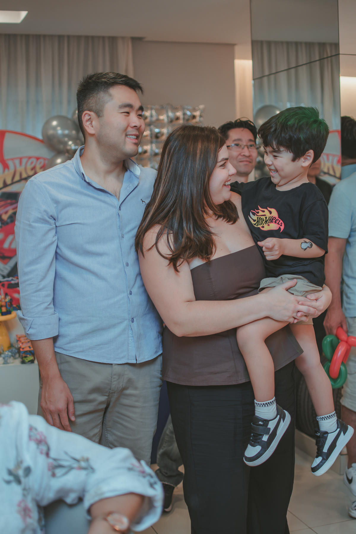 Uma familia abraçada e sorrindo, durante retrospectiva em festa de aniversário infantil.