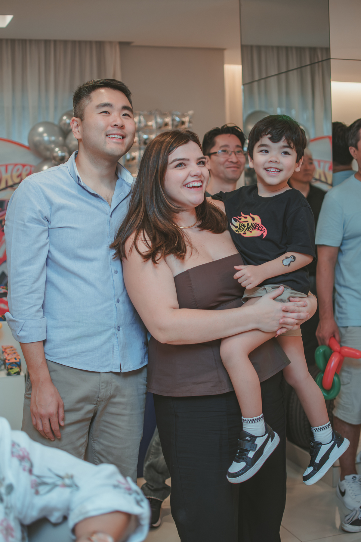 Uma familia abraçada e sorrindo, durante retrospectiva em festa de aniversário infantil.