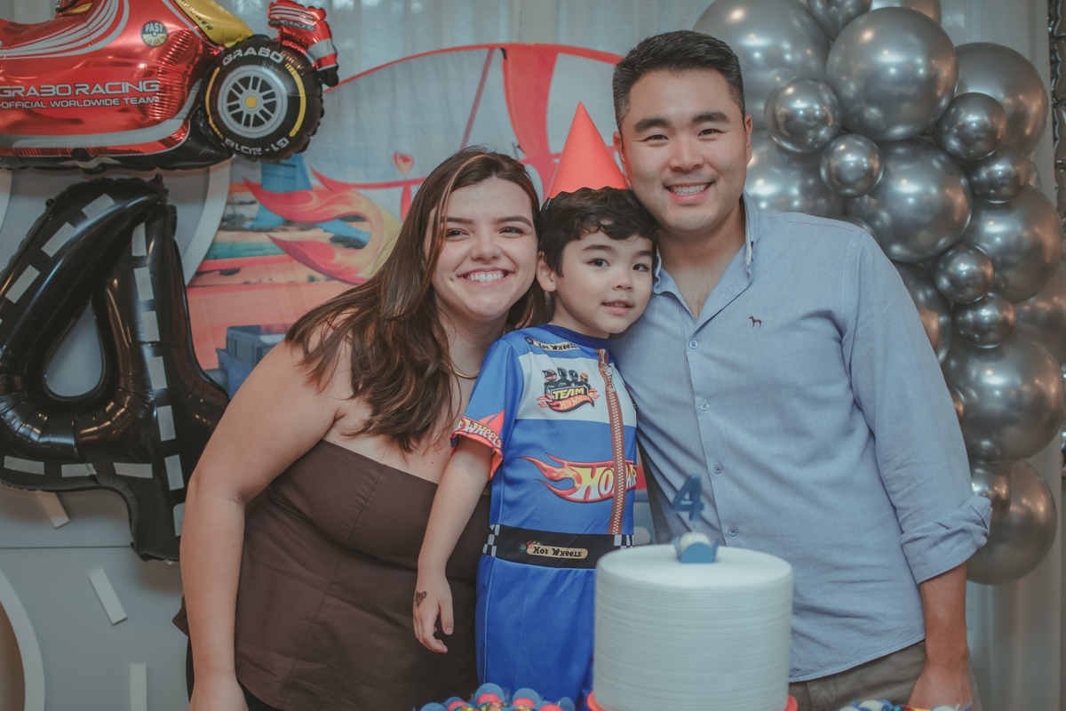 Uma familia durante o momento do parabéns na festa de aniversário de 4 anos do filho.