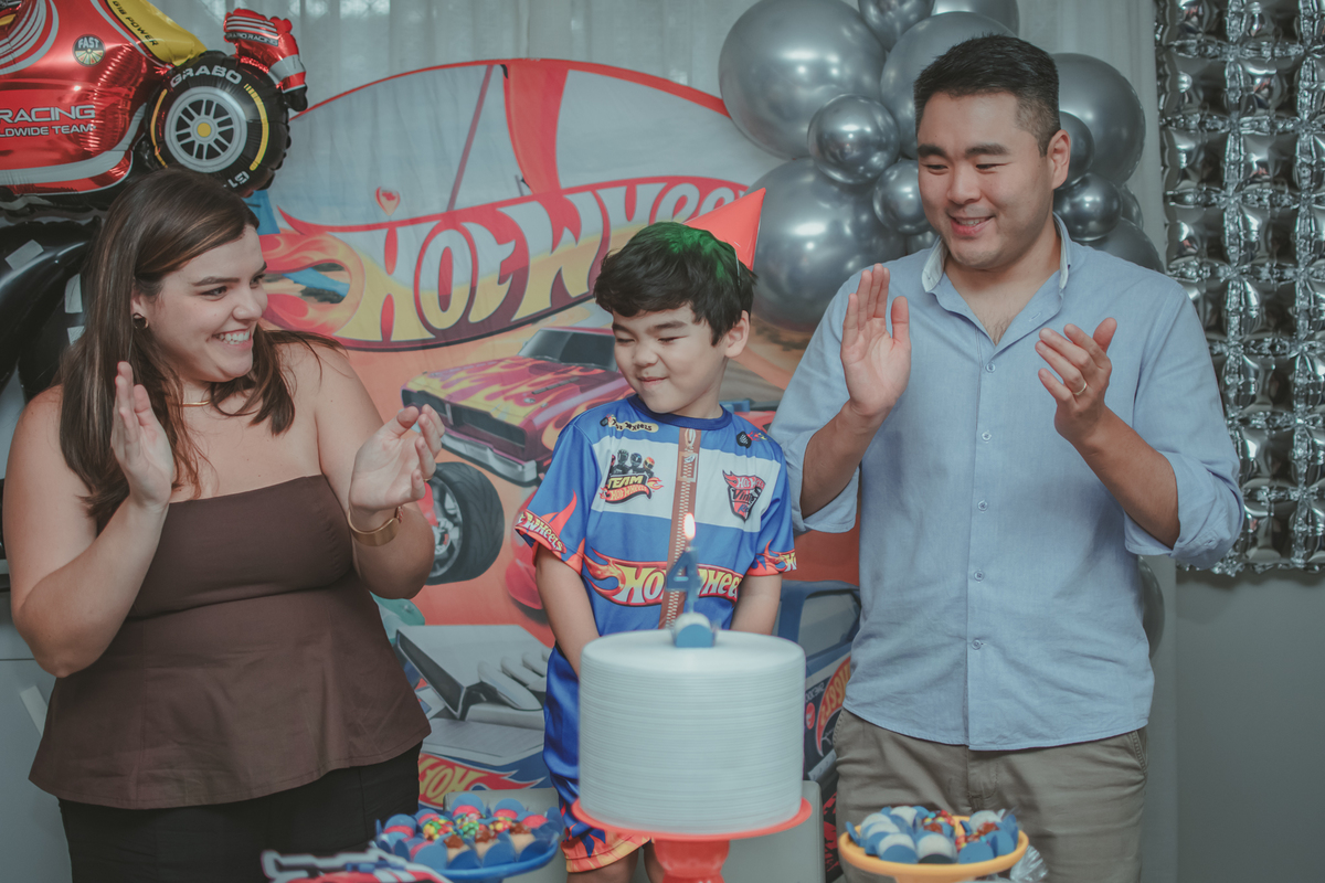 Uma familia durante o momento do parabéns na festa de aniversário de 4 anos do filho.