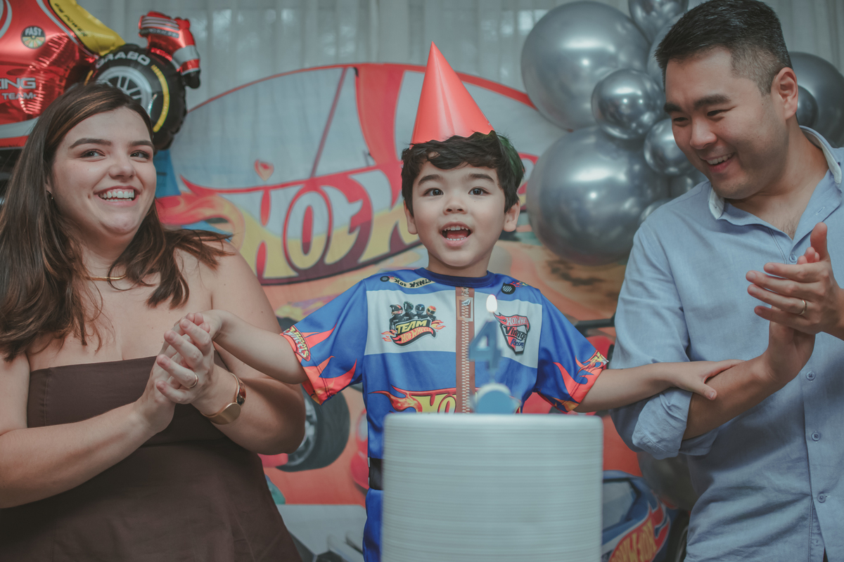 Uma familia durante o momento do parabéns na festa de aniversário de 4 anos do filho.