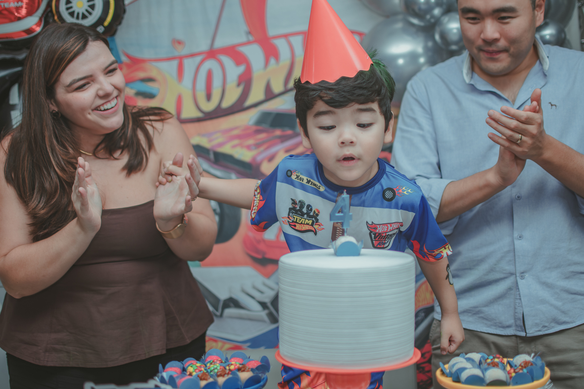 Uma familia durante o momento do parabéns na festa de aniversário de 4 anos do filho.