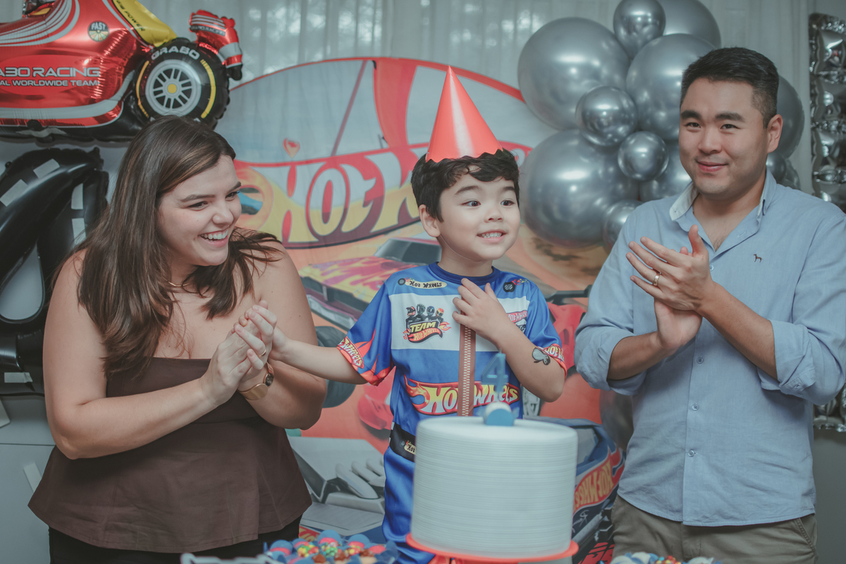Uma familia durante o momento do parabéns na festa de aniversário de 4 anos do filho.
