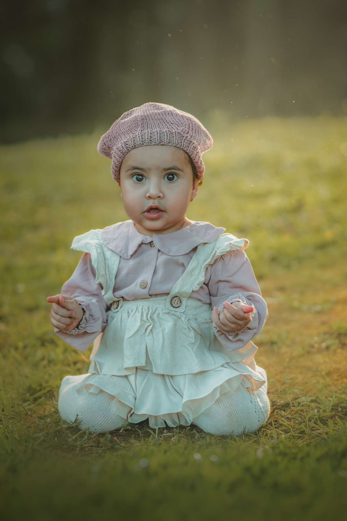 Uma bebê vestida de camponesa, sentada na grama do parque durante seu ensaio fotográfico de 1 ano.