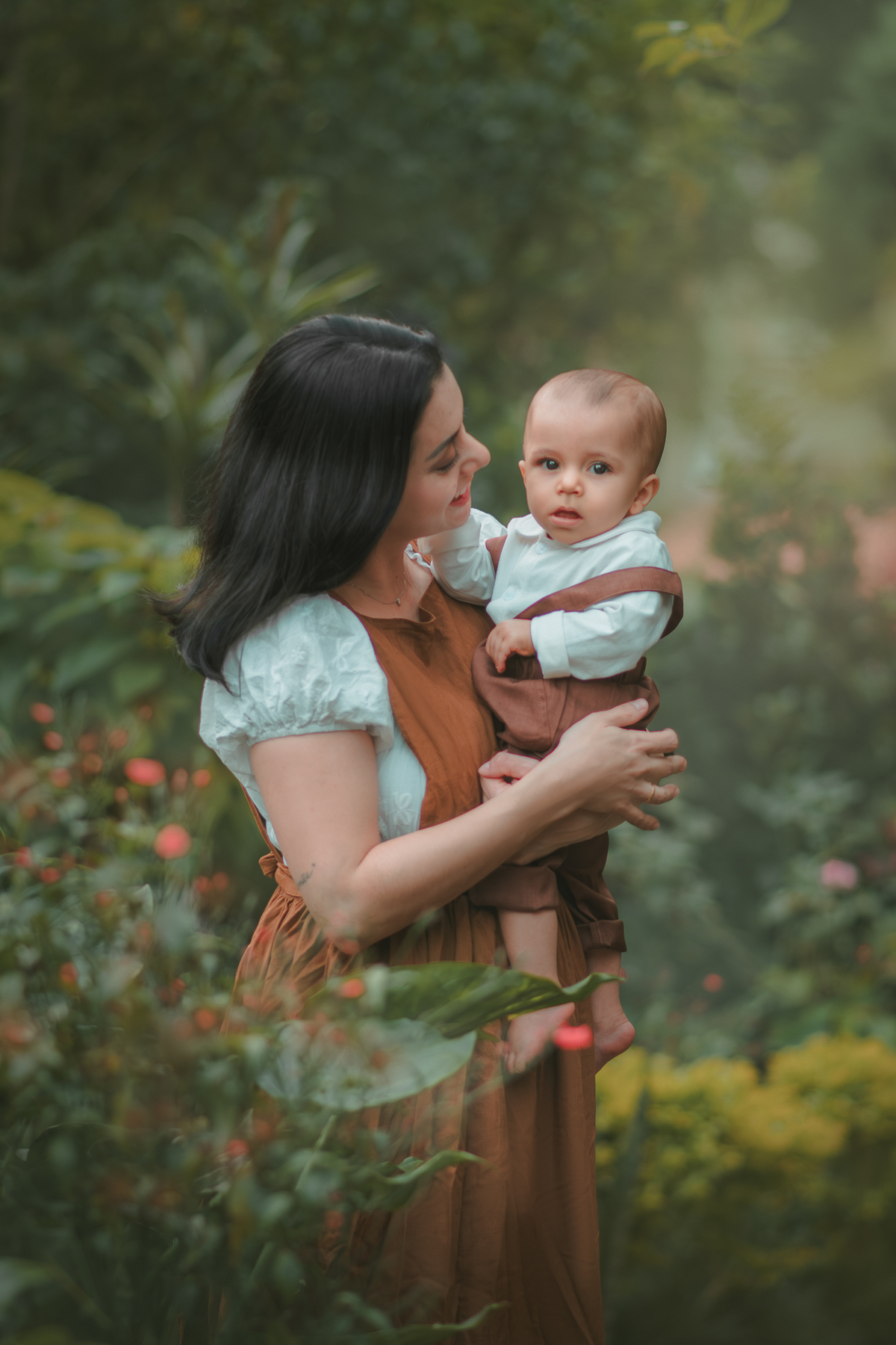 Uma mãe com seu bebê ambos vestidos de camponeses, durante um ensaio fotográfico de 1 ano na natureza.