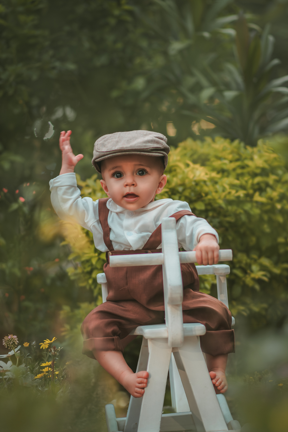 Um bebê vestido com roupas vintage, uma boina e brincando em uma cavalinho de madeira durante seu ensaio fotográfico de 1 ano.