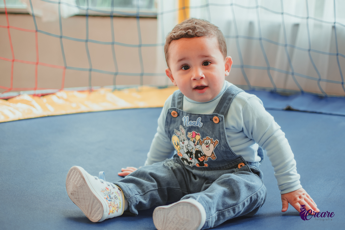 Um bebê de 1 ano brincando em uma cama elástica durante sua festa de aniversário.
