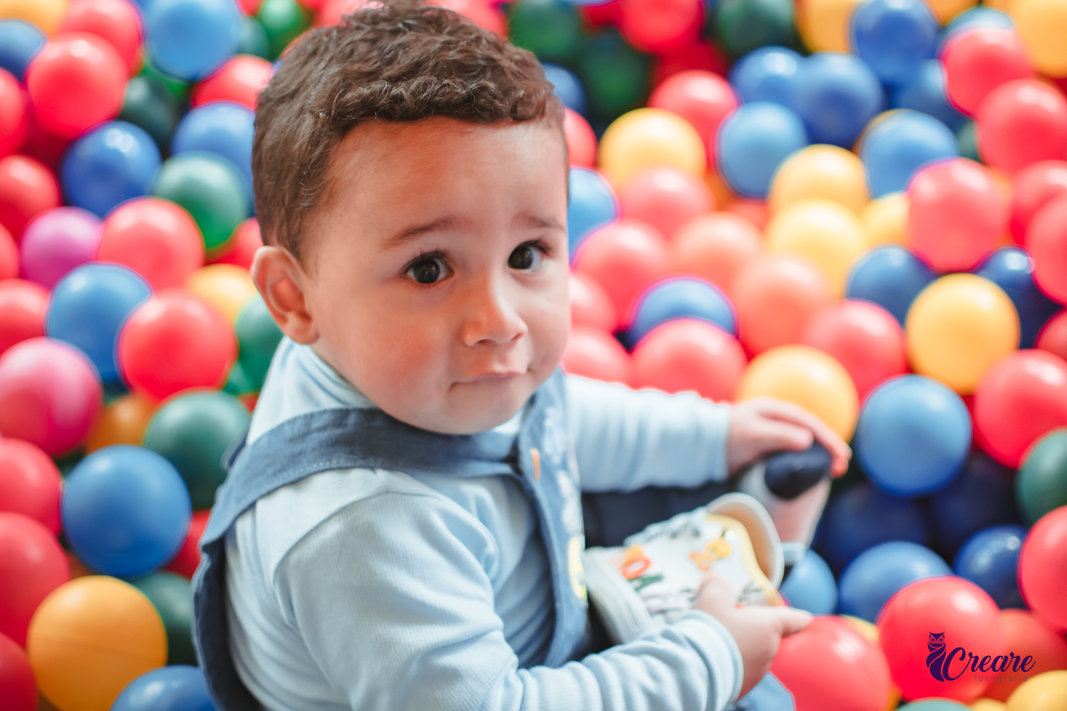 Um bebê de 1 ano brincando em uma piscina de bolinhas durante sua festa de aniversário.