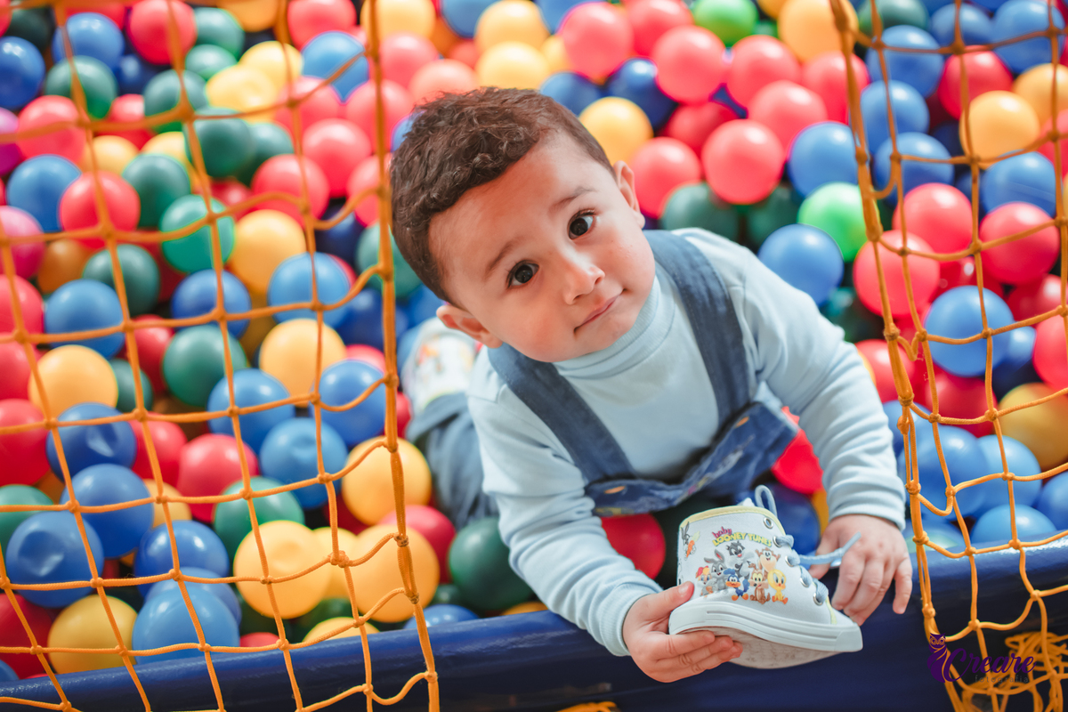 Um bebê de 1 ano brincando em uma piscina de bolinhas durante sua festa de aniversário.