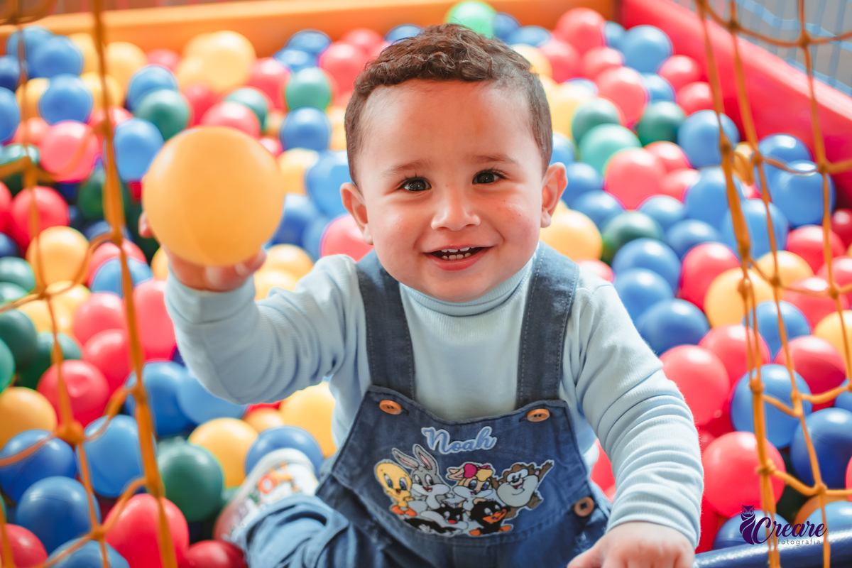 Um bebê de 1 ano brincando em uma piscina de bolinhas durante sua festa de aniversário.