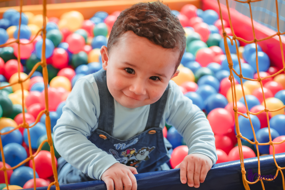 Um bebê de 1 ano brincando em uma piscina de bolinhas durante sua festa de aniversário.