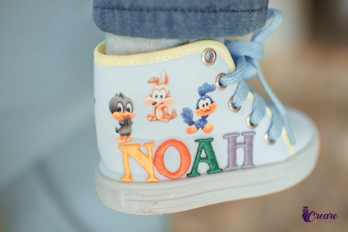 Detalhes do sapatinho de um bebê personalizado com o tema Baby Looney tunes e escirto Noah.