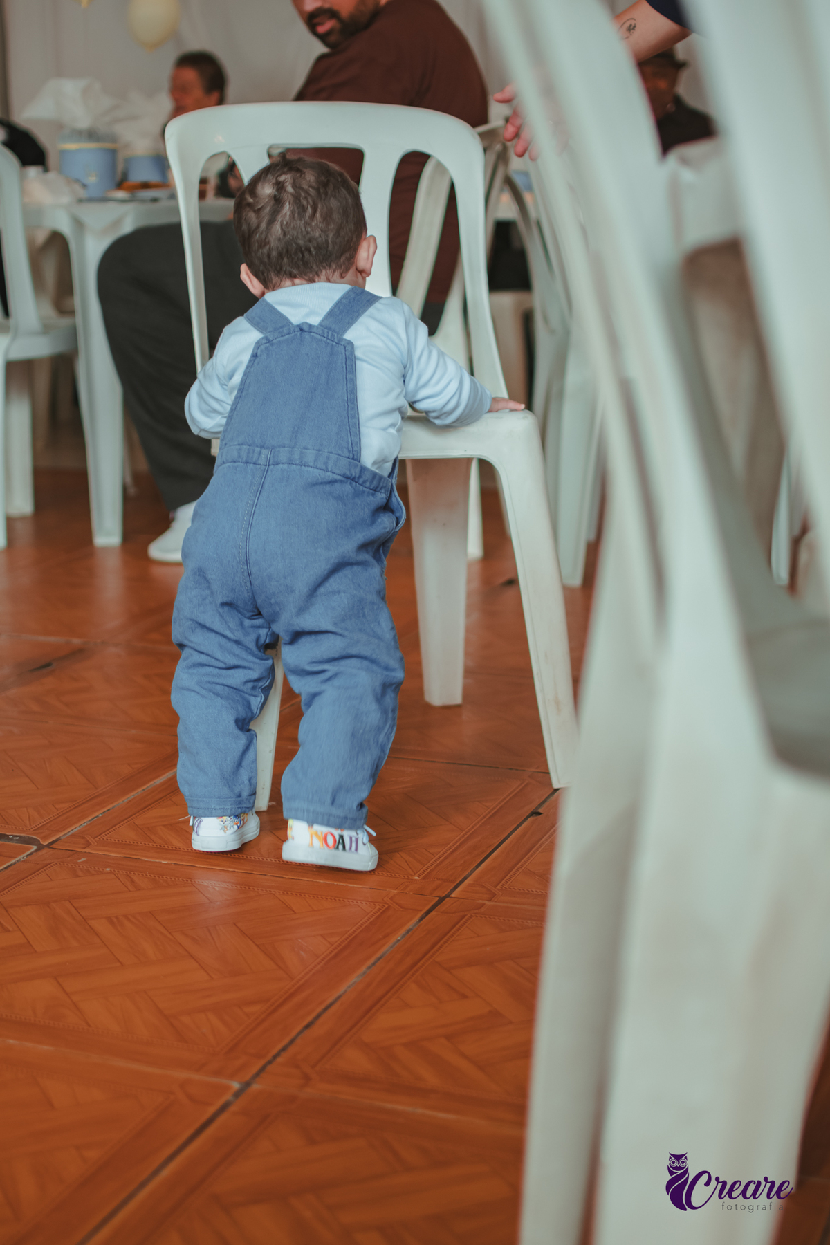 Um bebê brincando de empurrar cadeira durante sua festa de aniversário de 1 ano.