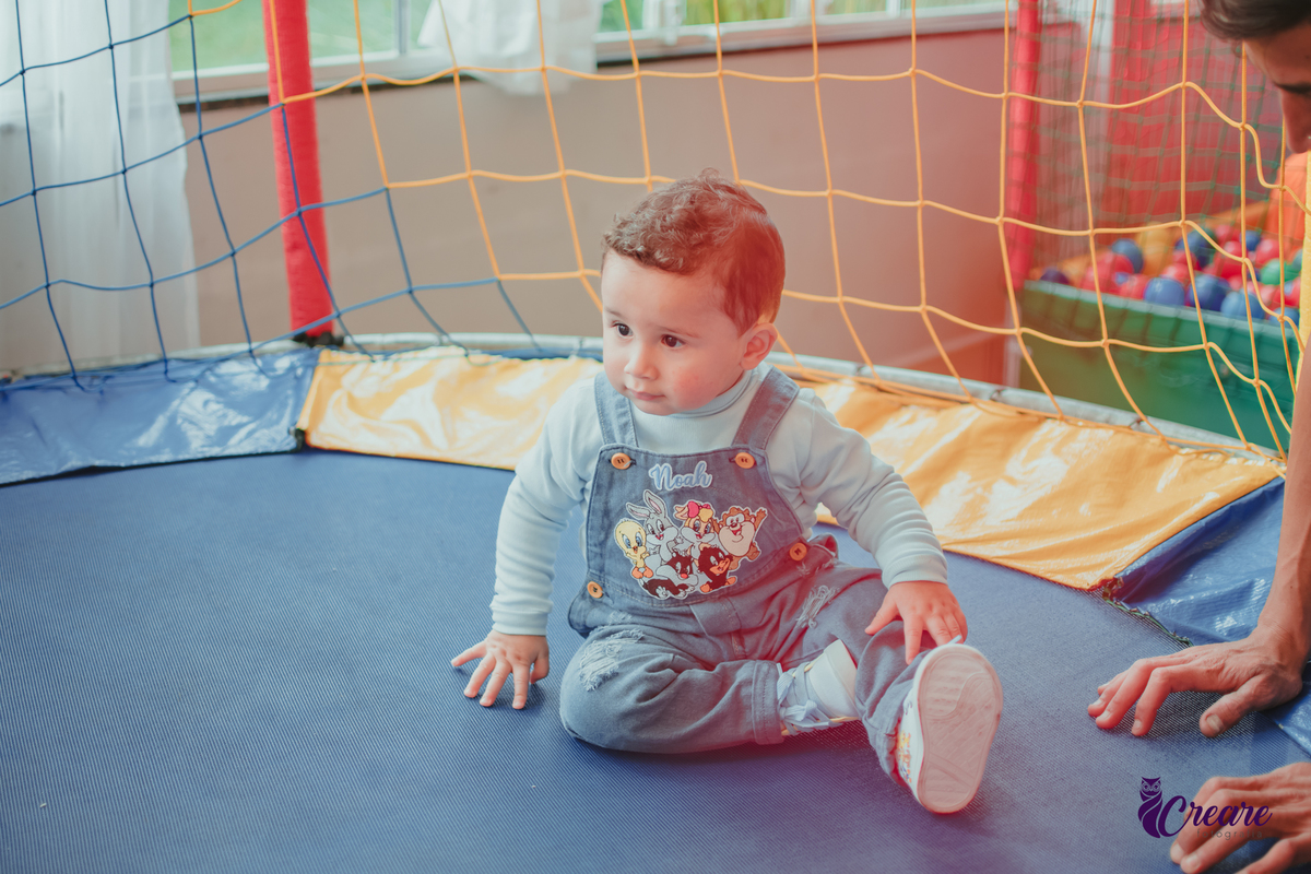 Um bebê de 1 ano brincando em uma cama elástica durante sua festa de aniversário.